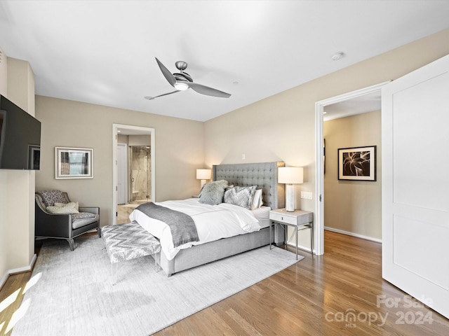 bedroom with ensuite bath, ceiling fan, and hardwood / wood-style floors