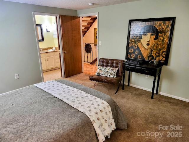 carpeted bedroom with connected bathroom, sink, and a textured ceiling