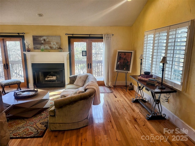 living room featuring lofted ceiling, light wood-type flooring, and french doors