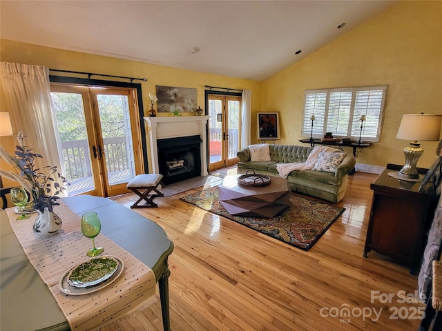 living room featuring light hardwood / wood-style flooring, a wealth of natural light, high vaulted ceiling, and french doors