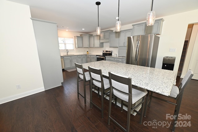 kitchen featuring a kitchen island, a kitchen breakfast bar, appliances with stainless steel finishes, and dark wood-type flooring