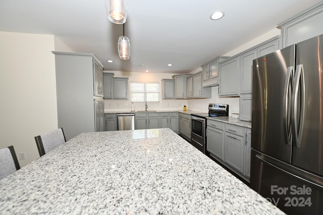 kitchen with decorative light fixtures, a breakfast bar, light stone countertops, gray cabinetry, and appliances with stainless steel finishes