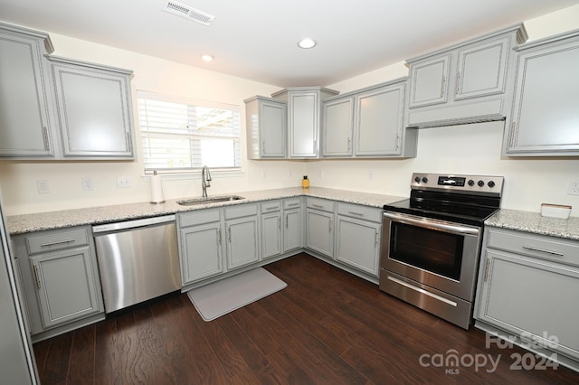 kitchen featuring gray cabinets, dark hardwood / wood-style flooring, appliances with stainless steel finishes, sink, and light stone counters