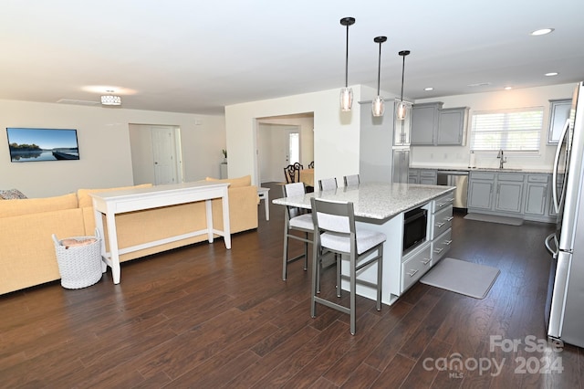 kitchen with sink, appliances with stainless steel finishes, dark hardwood / wood-style floors, gray cabinetry, and pendant lighting