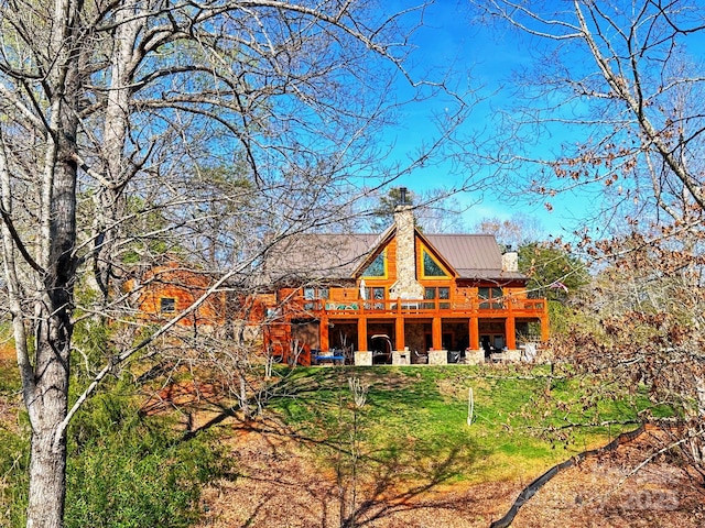 back of property featuring a deck and a lawn