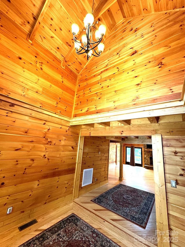 unfurnished living room featuring wood ceiling, wooden walls, high vaulted ceiling, and beamed ceiling