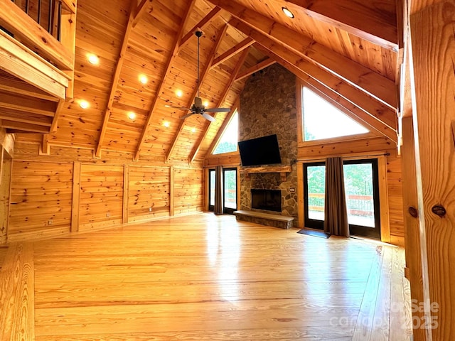 unfurnished living room with wood ceiling, beam ceiling, wooden walls, high vaulted ceiling, and light wood-type flooring