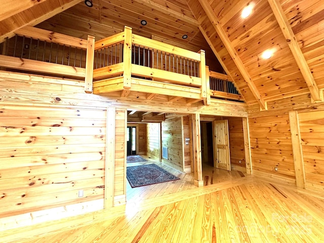 interior space featuring high vaulted ceiling, wood walls, wood-type flooring, wooden ceiling, and beam ceiling