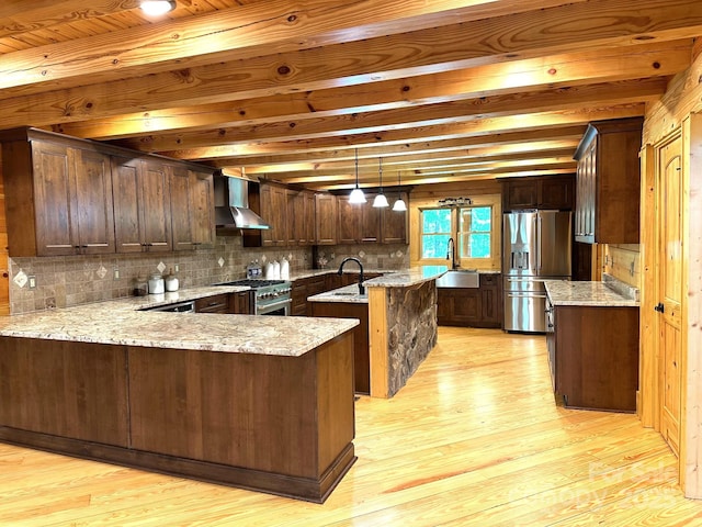 kitchen with wall chimney exhaust hood, sink, decorative light fixtures, appliances with stainless steel finishes, and kitchen peninsula