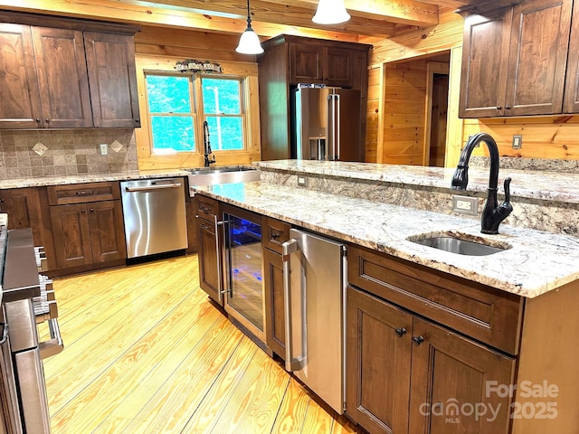 kitchen featuring appliances with stainless steel finishes, light stone countertops, sink, and hanging light fixtures