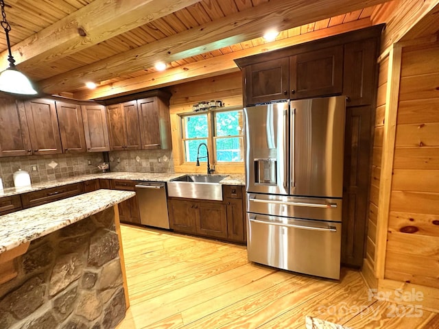 kitchen featuring pendant lighting, sink, light stone countertops, and appliances with stainless steel finishes