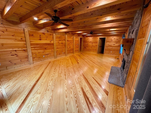 interior space with a fireplace, light wood-type flooring, ceiling fan, wood ceiling, and beam ceiling