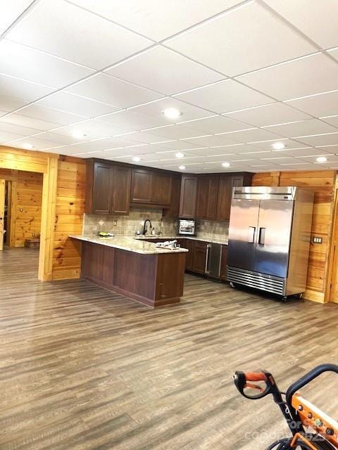 kitchen featuring dark brown cabinets, stainless steel built in fridge, kitchen peninsula, and light wood-type flooring