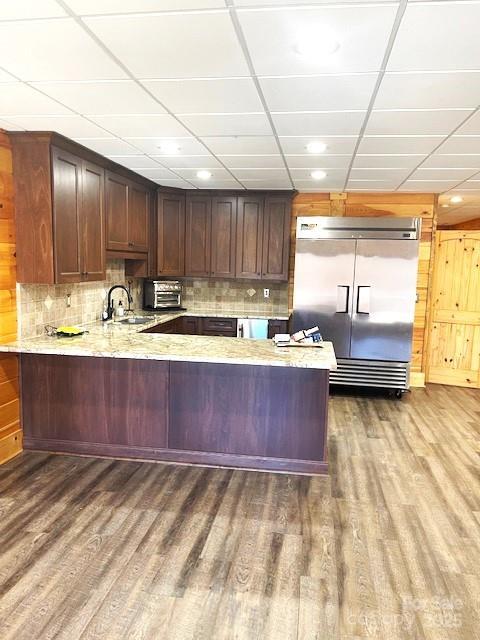 kitchen with wood-type flooring, stainless steel built in fridge, a paneled ceiling, and kitchen peninsula