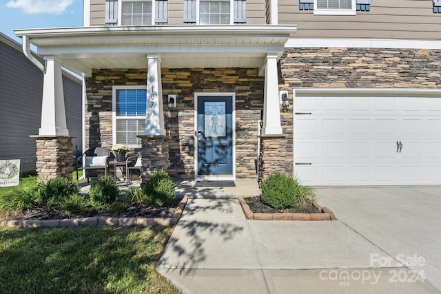 entrance to property featuring covered porch and a garage