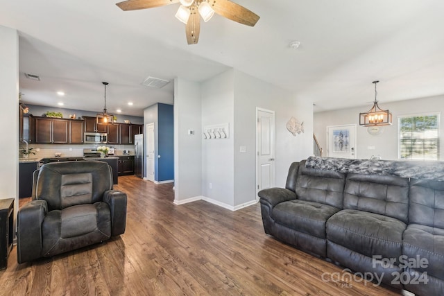 living room featuring ceiling fan with notable chandelier and dark hardwood / wood-style floors