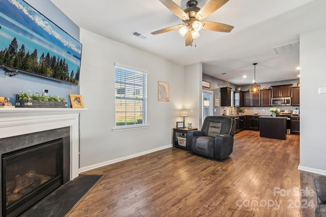 living room with ceiling fan, dark hardwood / wood-style floors, and sink