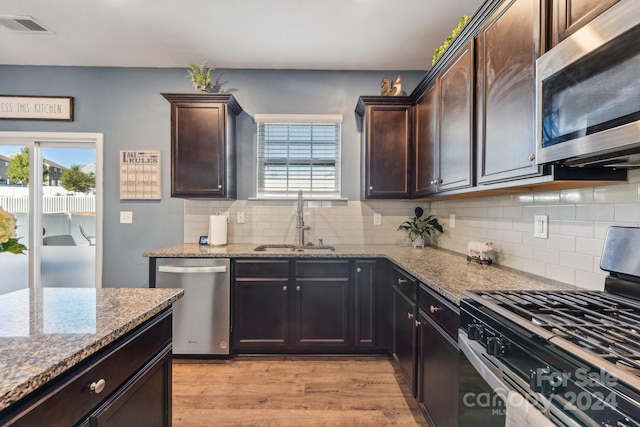 kitchen with appliances with stainless steel finishes, sink, light wood-type flooring, and dark brown cabinets