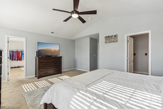 carpeted bedroom featuring ceiling fan, a closet, vaulted ceiling, and a spacious closet