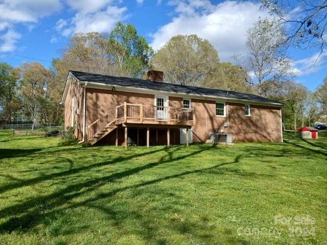 rear view of property featuring central AC, a wooden deck, and a lawn