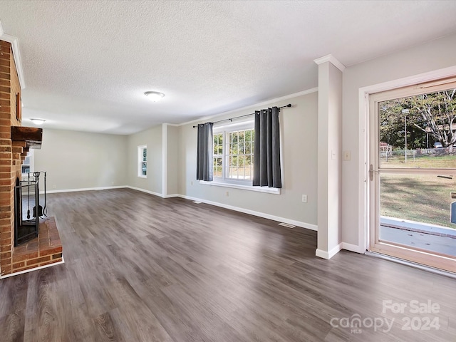 unfurnished living room with ornamental molding, a textured ceiling, a fireplace, and dark hardwood / wood-style floors