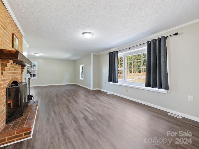 unfurnished living room with dark hardwood / wood-style floors, ornamental molding, a textured ceiling, and a fireplace