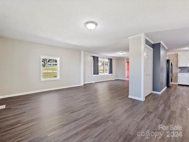 unfurnished living room with crown molding, hardwood / wood-style floors, a textured ceiling, and a wealth of natural light