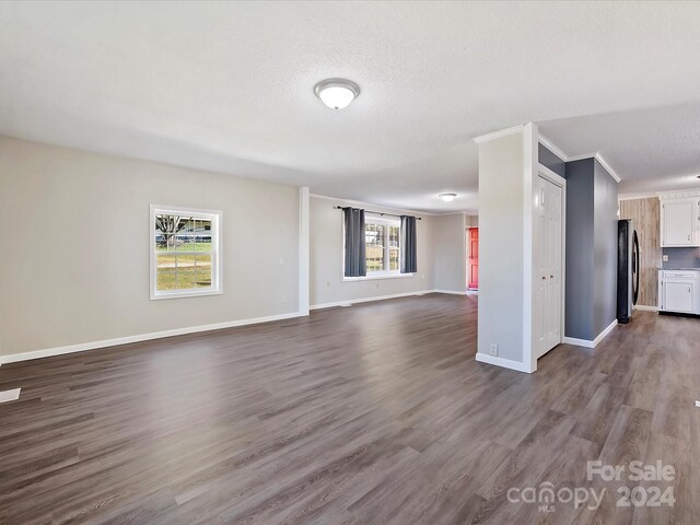 111 Bobby Lee Ln Unit 18, Mooresville, NC 28115 - unfurnished living room featuring dark wood-style flooring, a textured ceiling, baseboards, and ornamental molding