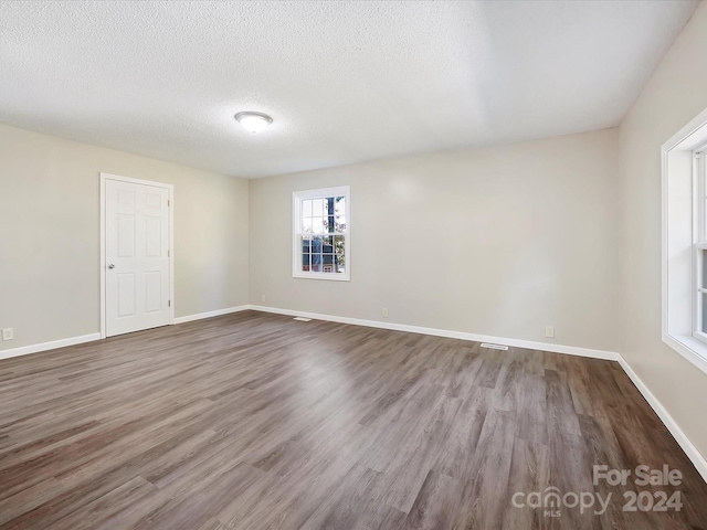 empty room with hardwood / wood-style floors and a textured ceiling