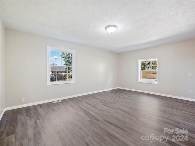 spare room featuring a textured ceiling, plenty of natural light, and dark hardwood / wood-style floors