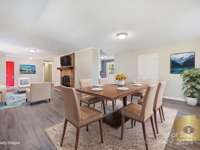 dining area with hardwood / wood-style floors, a brick fireplace, and a textured ceiling