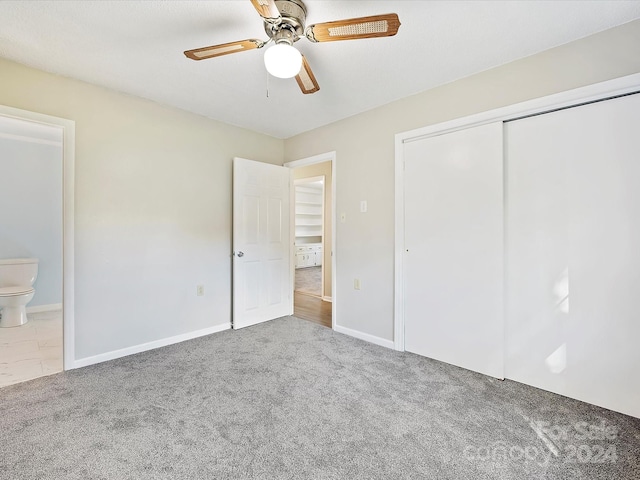 unfurnished bedroom featuring light carpet, a closet, connected bathroom, and ceiling fan