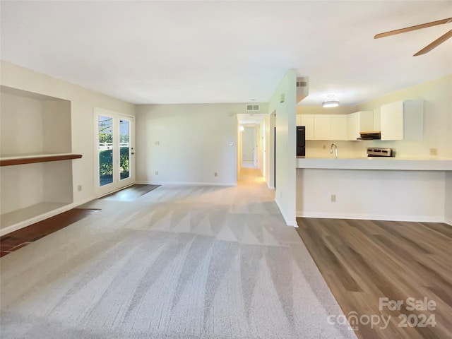 unfurnished living room featuring ceiling fan and light wood-type flooring