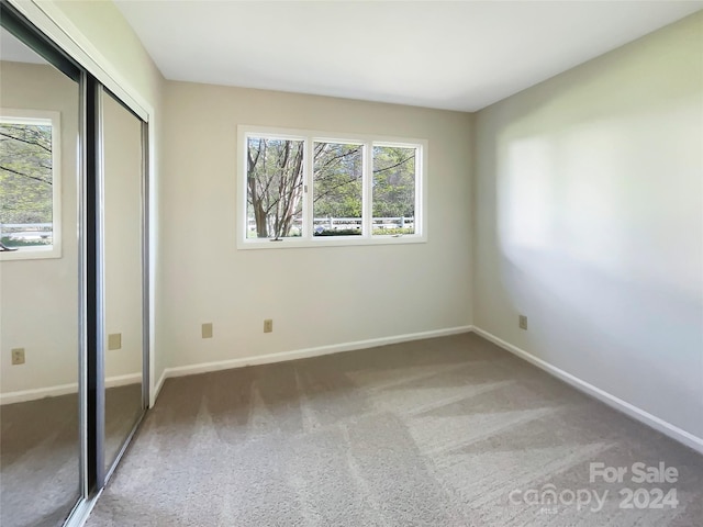 unfurnished bedroom featuring multiple windows, a closet, and dark colored carpet