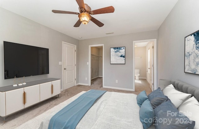 carpeted bedroom featuring ceiling fan, a walk in closet, a closet, and ensuite bath