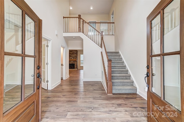 foyer entrance featuring light hardwood / wood-style flooring, a high ceiling, and a stone fireplace