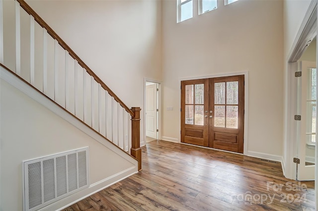 entryway with french doors, a high ceiling, and wood-type flooring