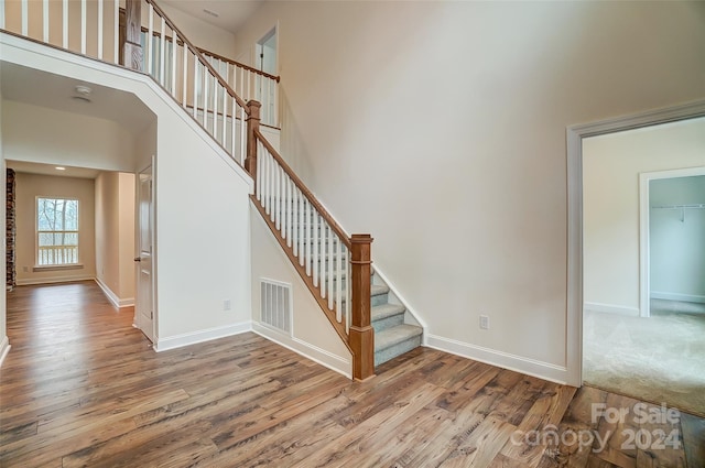 stairs with a high ceiling and hardwood / wood-style floors