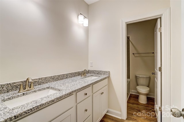 bathroom with double sink vanity, toilet, and hardwood / wood-style flooring