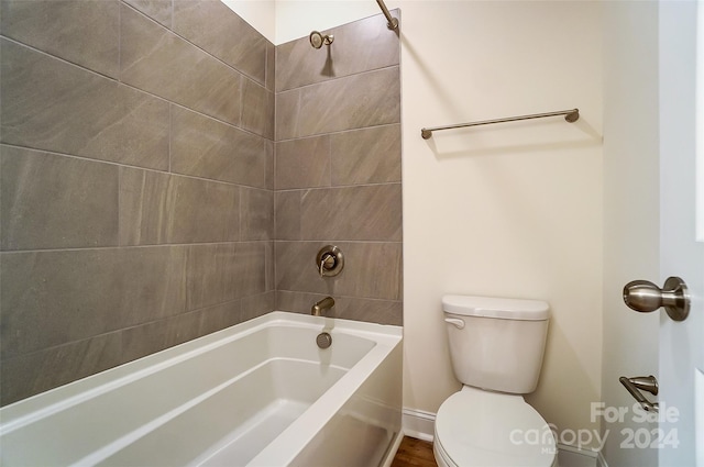 bathroom featuring tiled shower / bath combo, toilet, and wood-type flooring