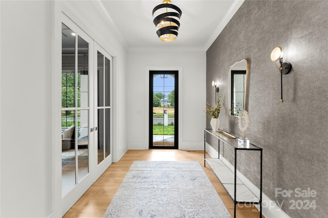 entrance foyer with ornamental molding, french doors, and light wood-type flooring