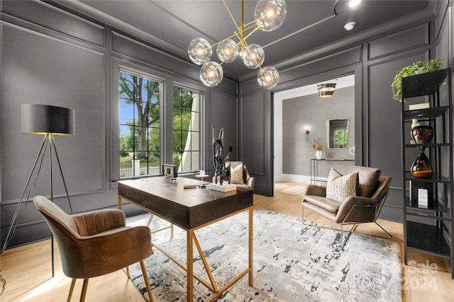 home office with a notable chandelier and light hardwood / wood-style flooring