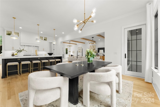 dining space featuring beam ceiling, a notable chandelier, sink, and light hardwood / wood-style flooring