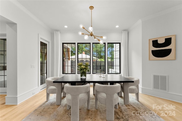 dining area featuring a chandelier, light hardwood / wood-style floors, and crown molding