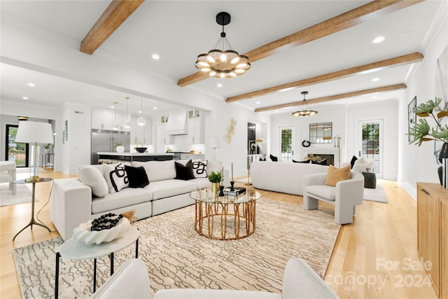 living room with beamed ceiling, plenty of natural light, and light wood-type flooring