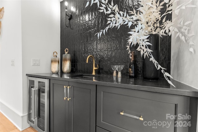 bar with gray cabinetry, sink, light hardwood / wood-style flooring, and tasteful backsplash