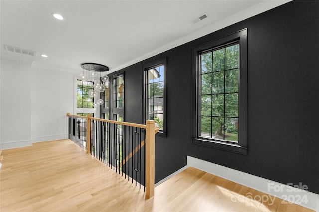 hallway featuring a notable chandelier, plenty of natural light, and light hardwood / wood-style flooring