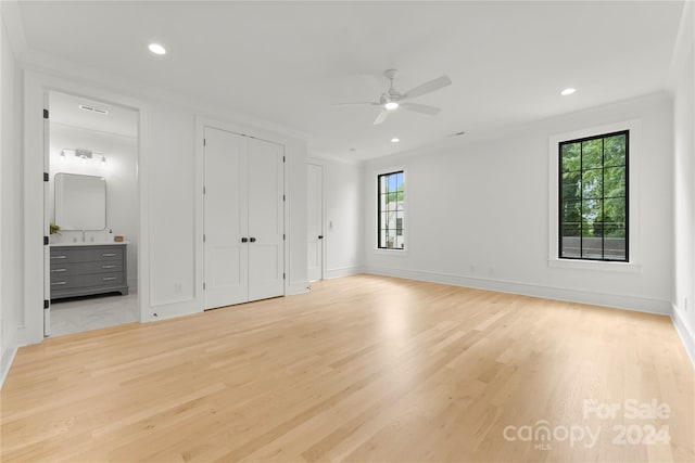 unfurnished bedroom with ceiling fan, crown molding, two closets, light wood-type flooring, and sink