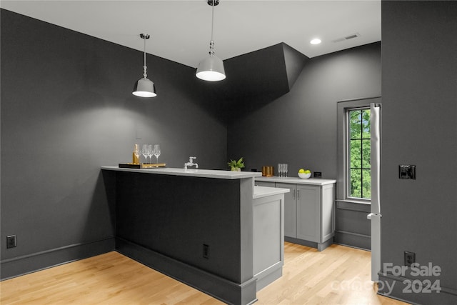 bar with gray cabinetry, light wood-type flooring, and pendant lighting