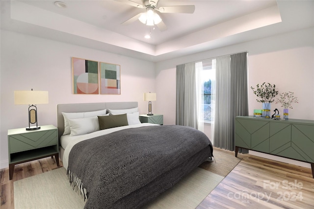 bedroom featuring hardwood / wood-style flooring, ceiling fan, and a raised ceiling